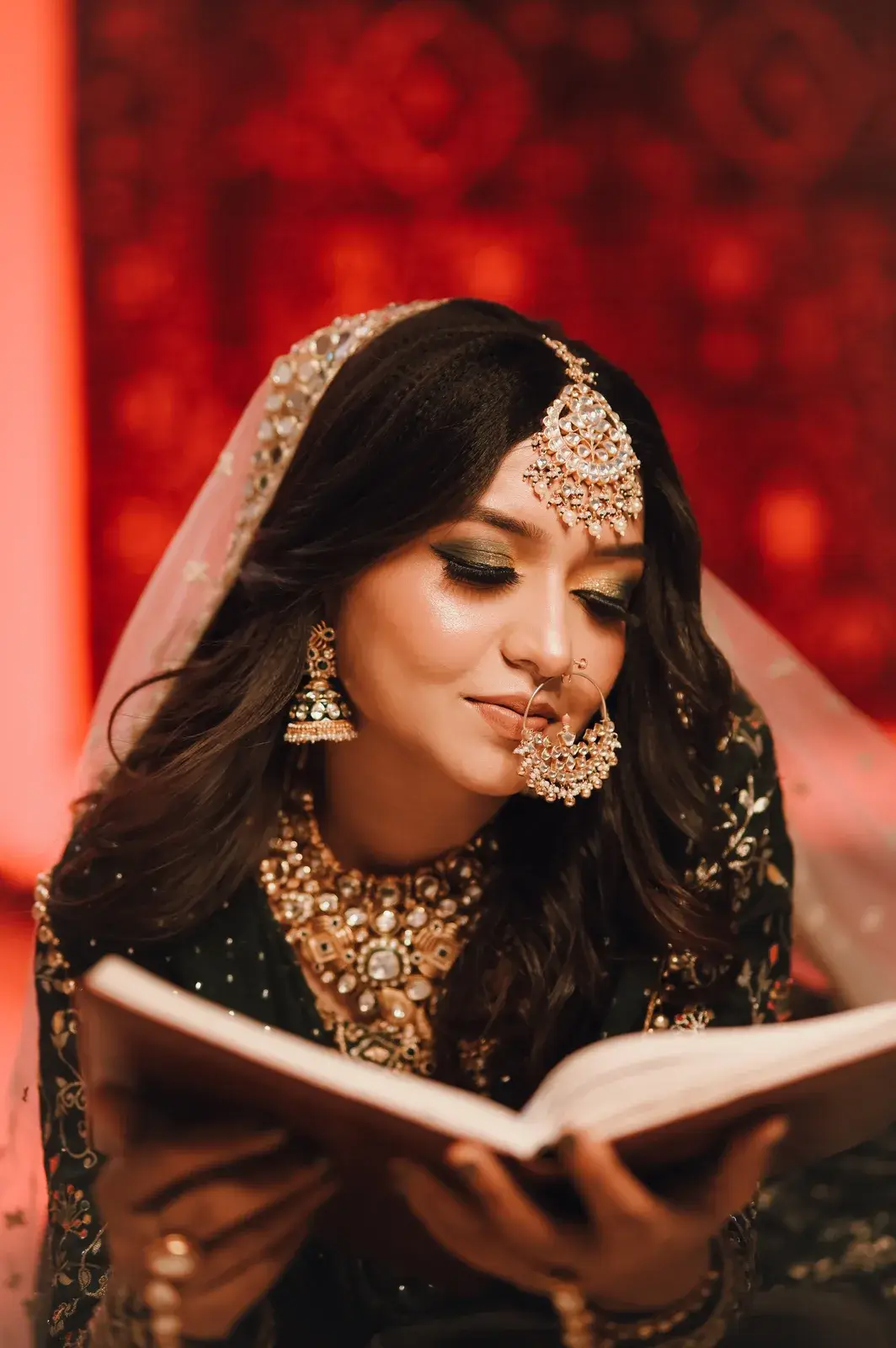 Bride in a green dupatta and polki jewellery reading a book
