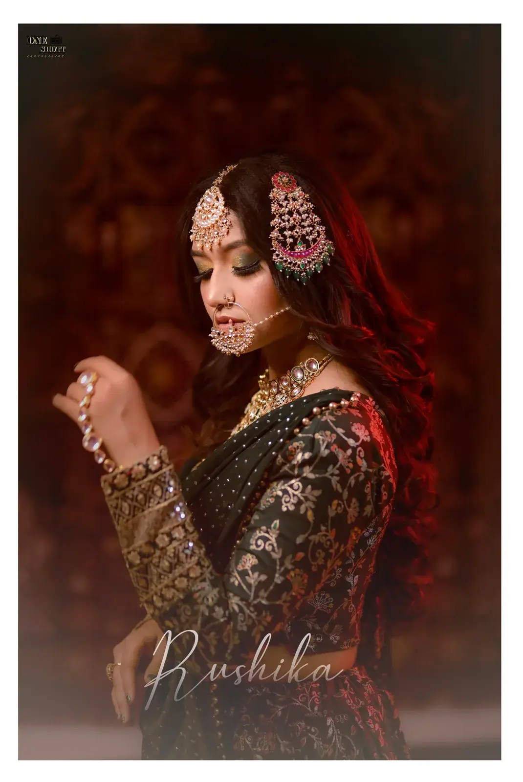 Bride in green with maang tikka and passa against a dark red backdrop
