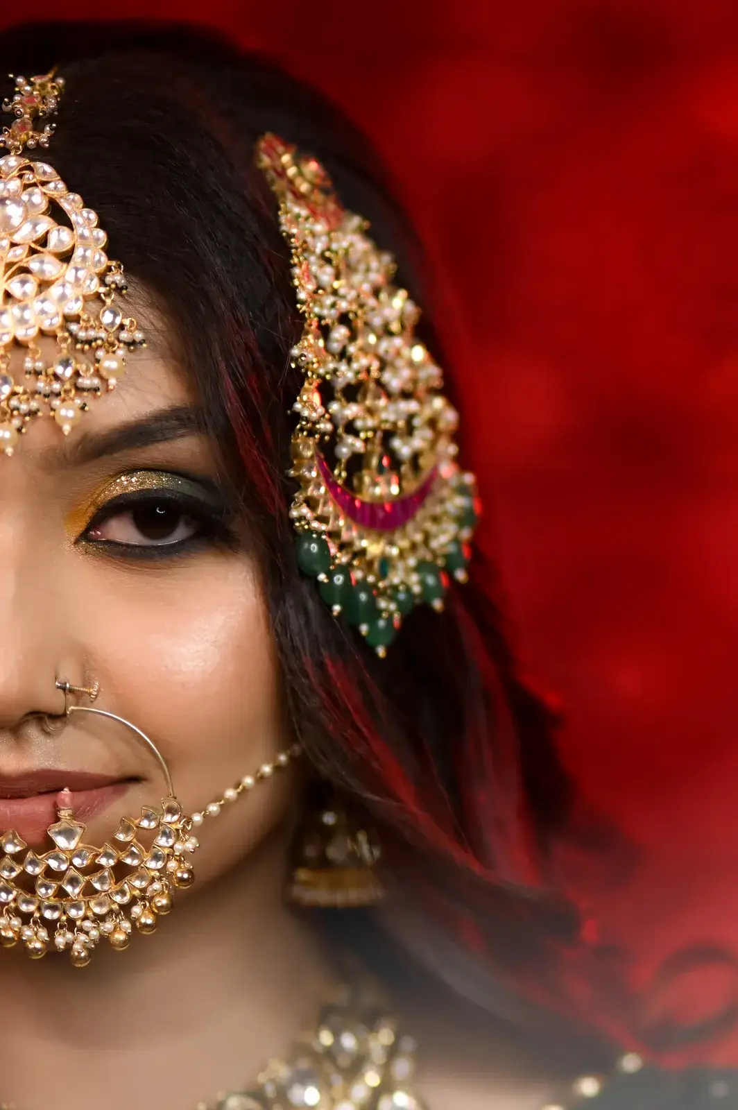 Close-up of a bride's nath, passa and eye makeup on a red background