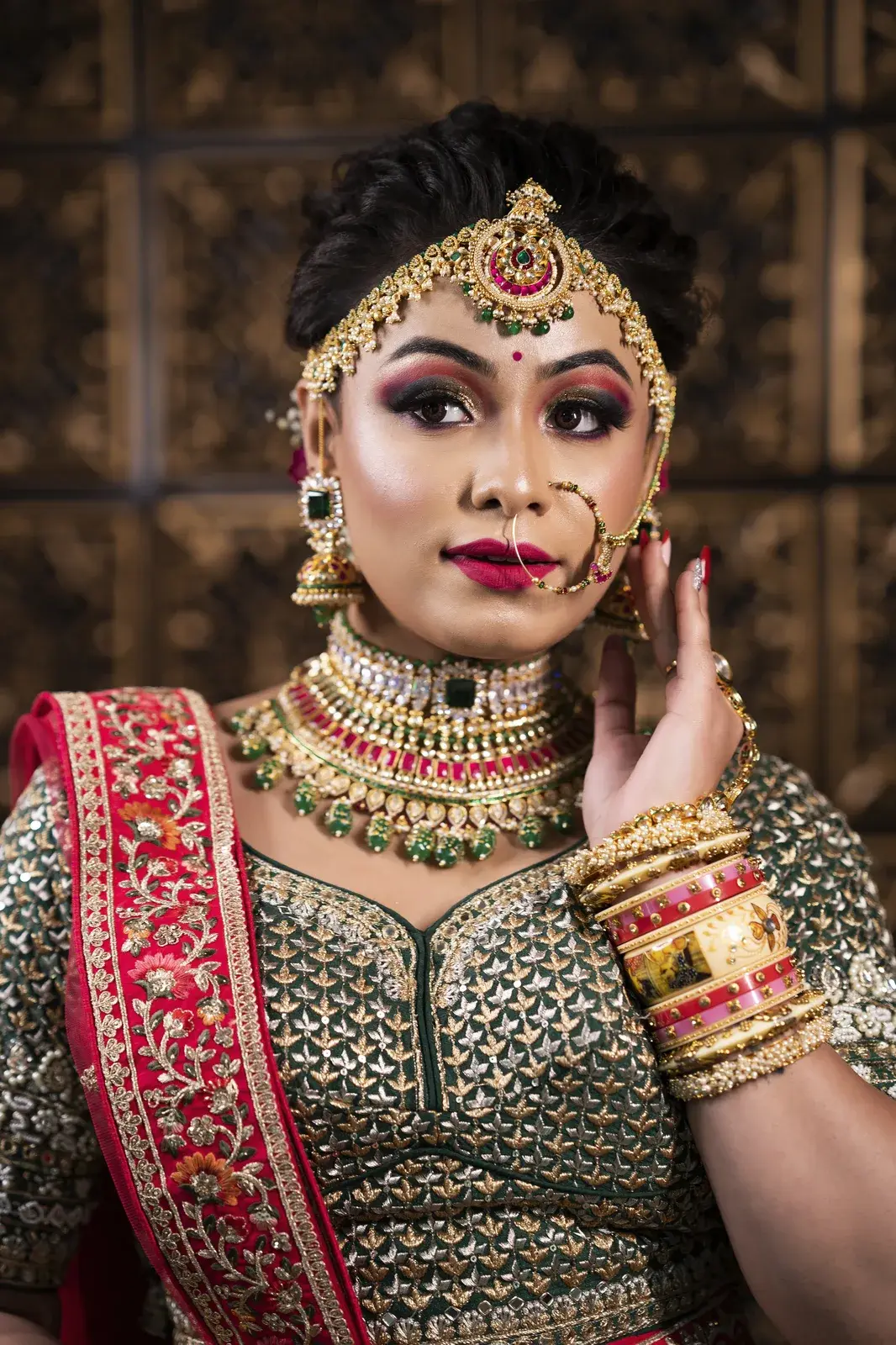 Bride with a red dupatta and stacked bangles touching her nath