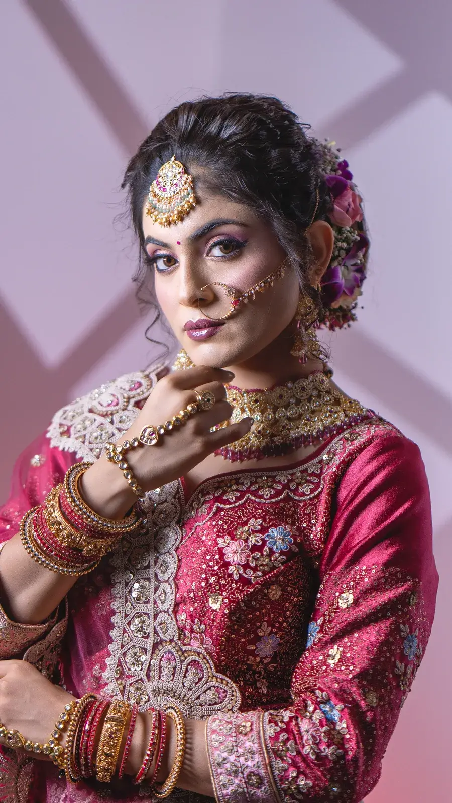 Bride in a magenta lehenga with pastel embroidery and a gold choker