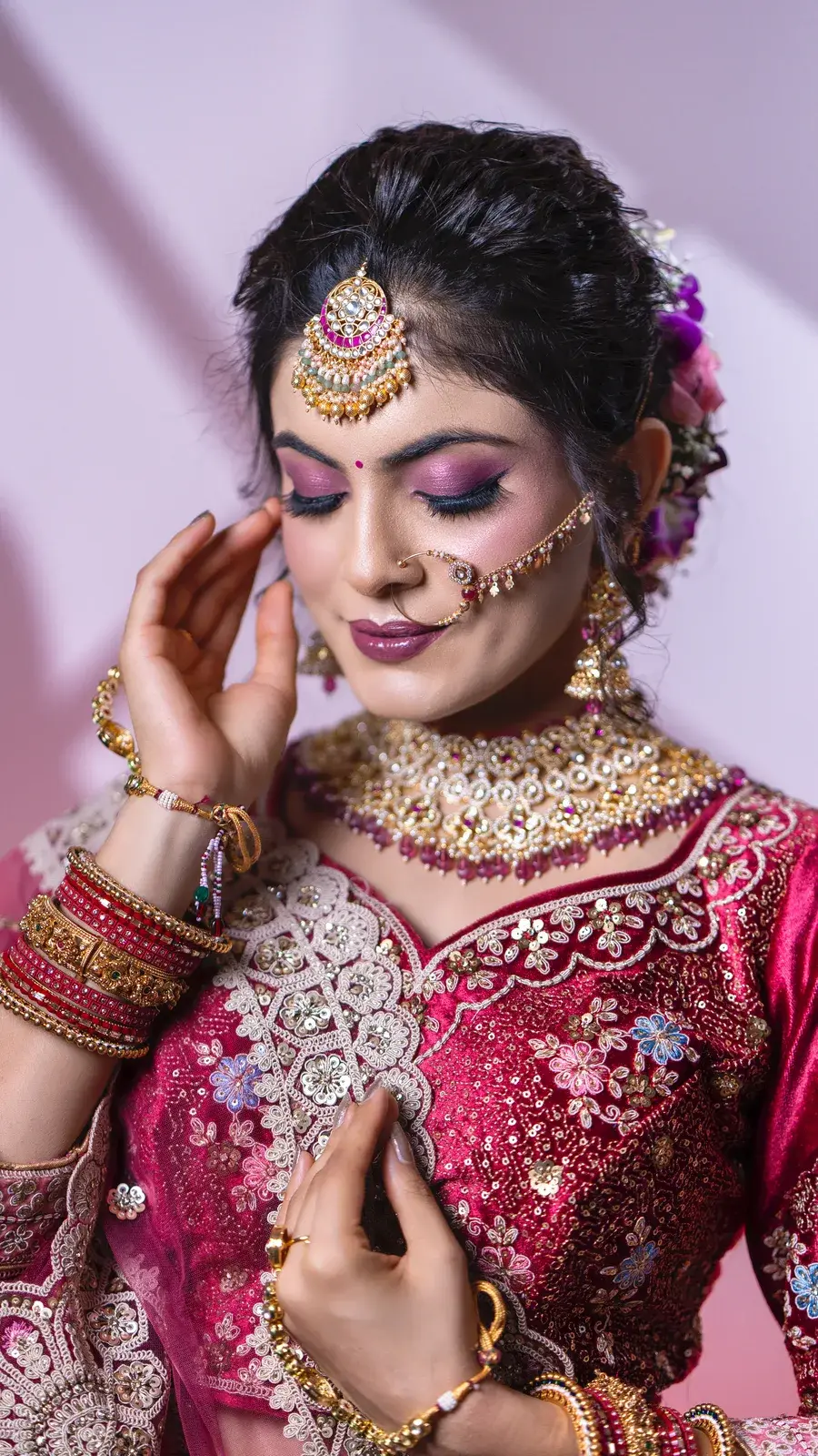 Close portrait of a bride in magenta with lilac eye makeup and maang tikka