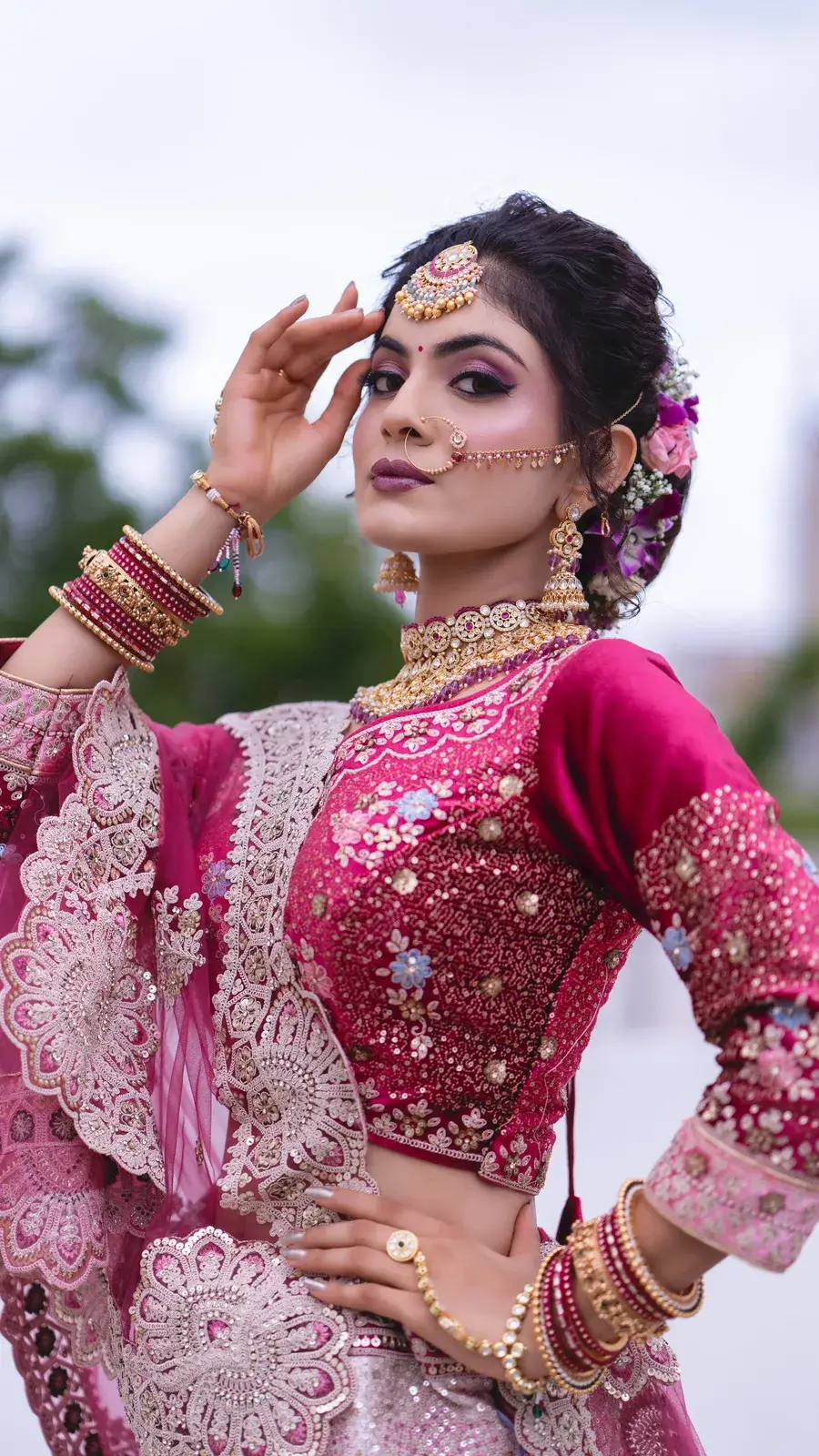 Bride in magenta outdoors with one hand raised to her hair