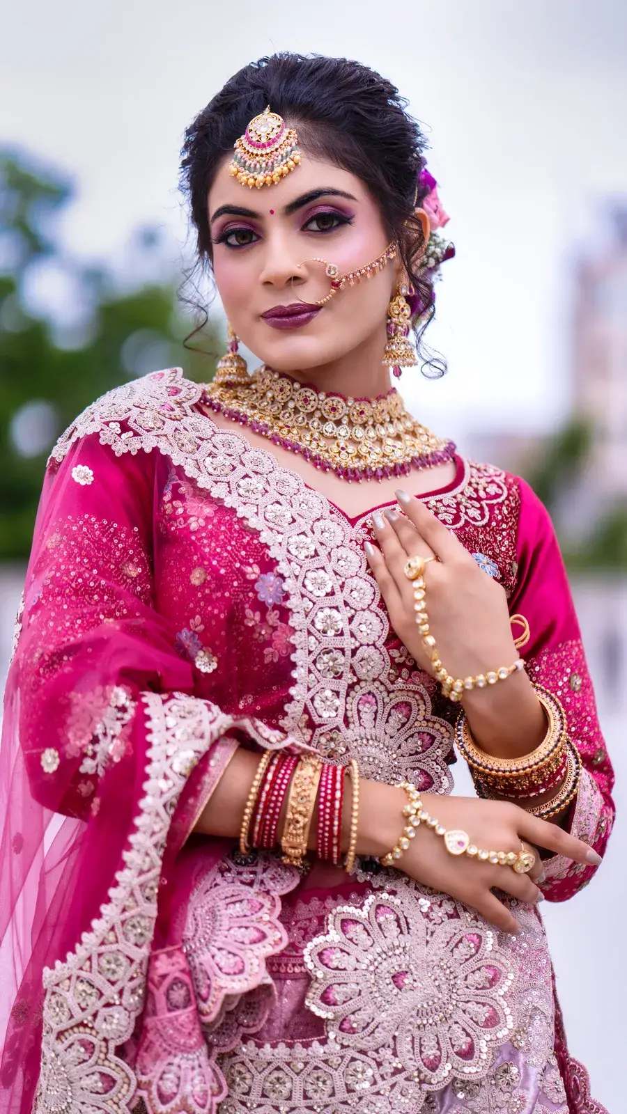 Bride in a magenta lehenga and net dupatta outdoors
