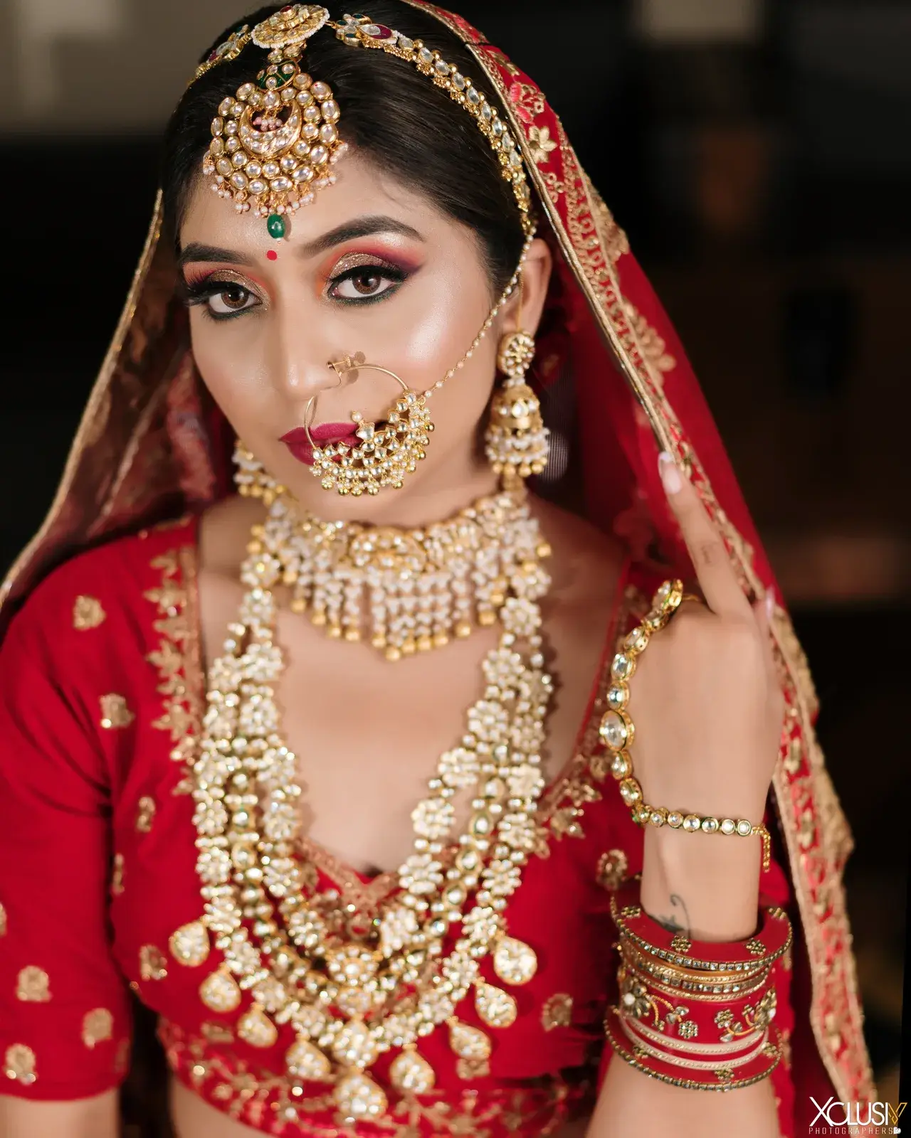Close portrait of a bride in a red dupatta with maang tikka and nath